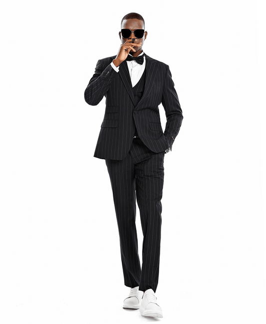A man wearing a 3-piece suit with a bowtie. Black suit with white pinstripes.